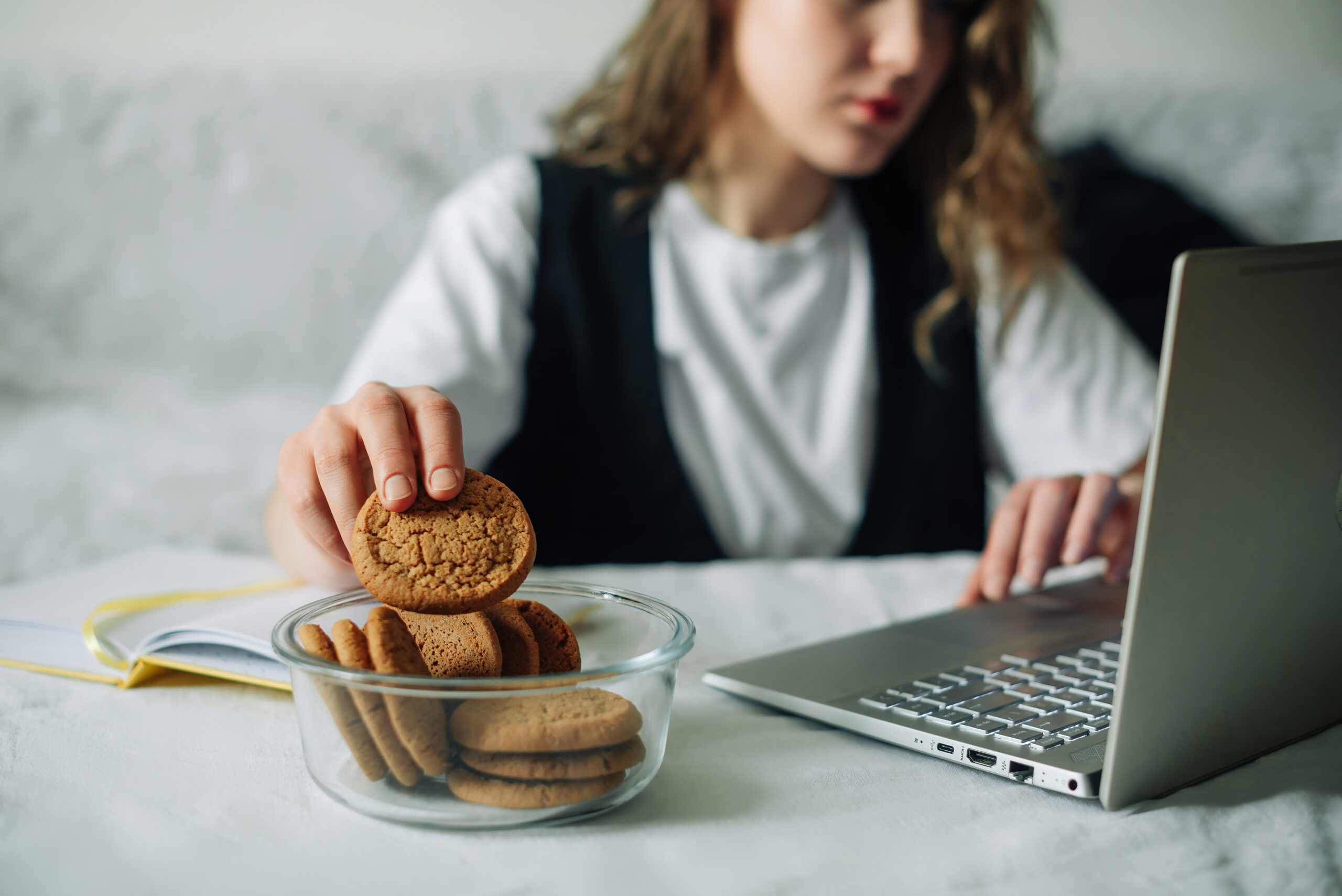 unbewusstes-essen-schlechte-angewohnheiten-selektiver-fokus-der-hand-einer-konzentrierten-frau-die-am-laptop-am