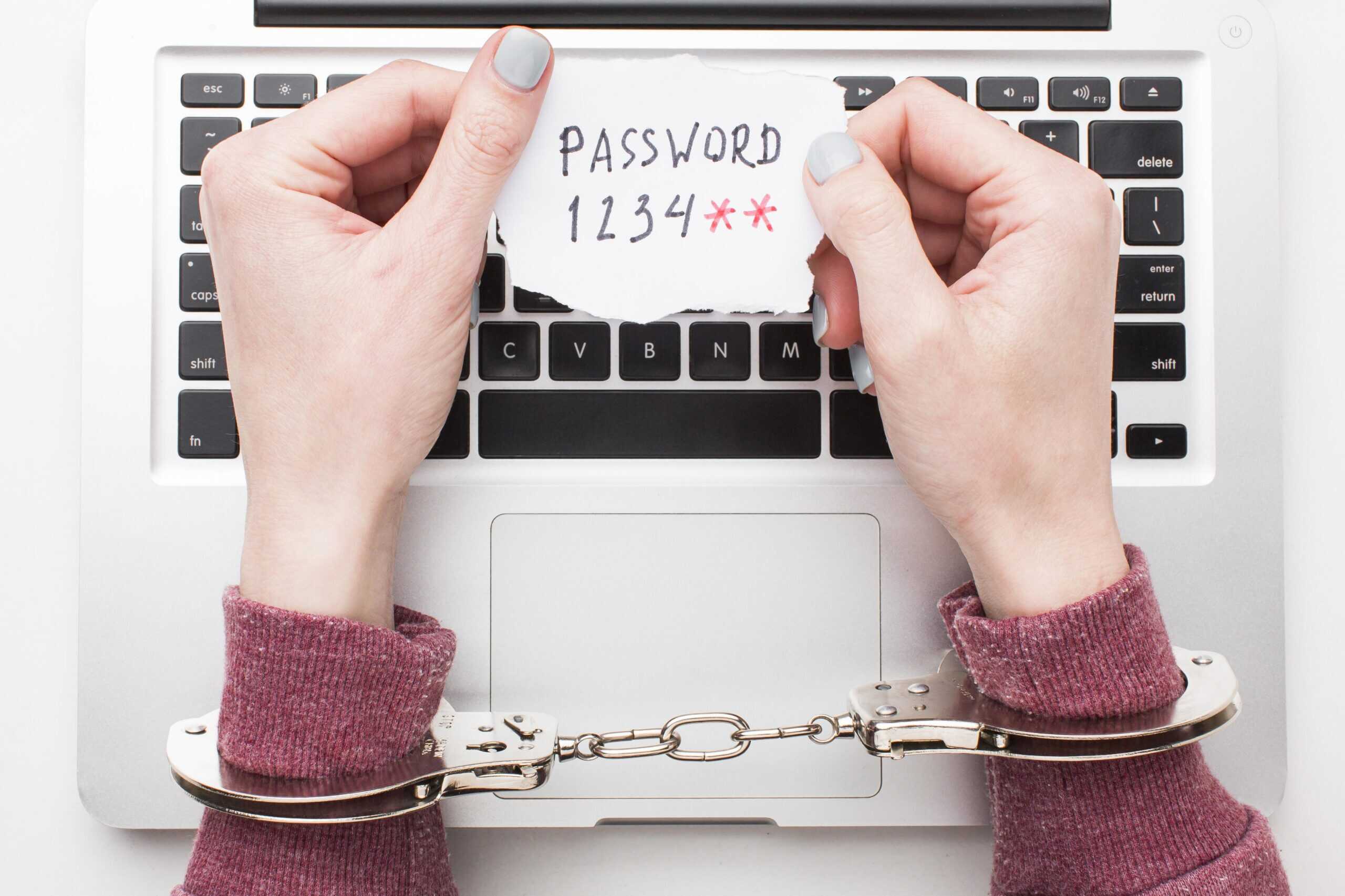 1 – draufsicht-der-hande-mit-handschellen-die-laptop-passwort-halten